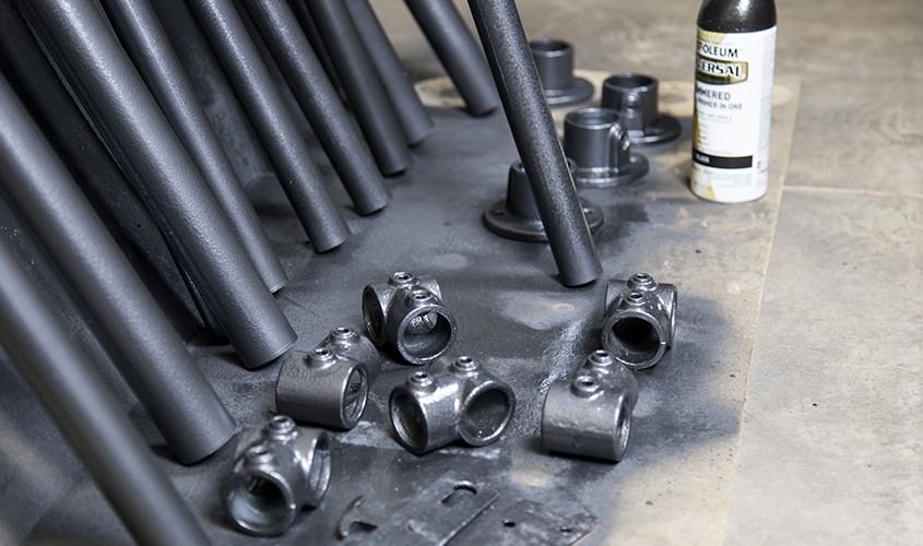 galvanized metal pipes being spray painted with metalic grey paint