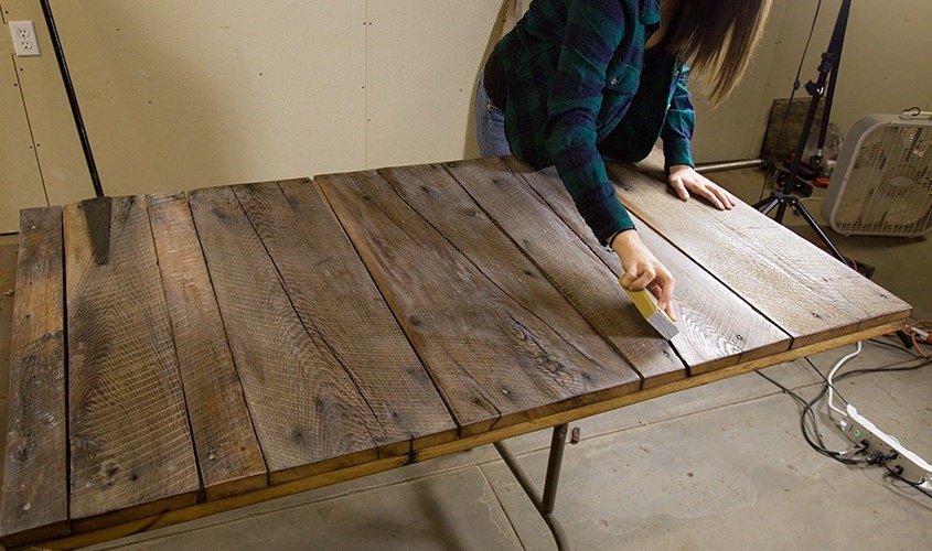 female using sanding block on old wood