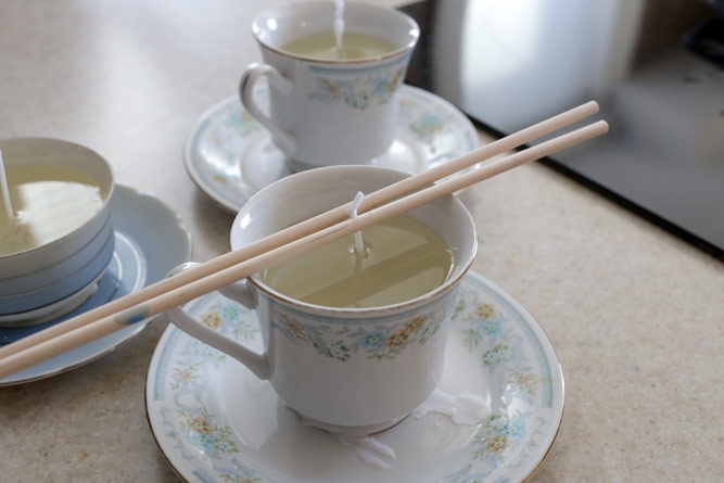 chopsticks balanced on top of teacup to held a candle wick while wax hardens