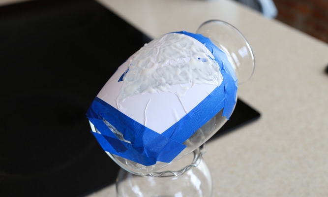 a clear glass vase with masking tape and etching cream applied
