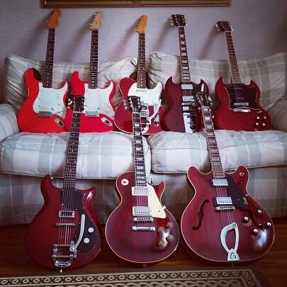 a large collection of red electric guitars